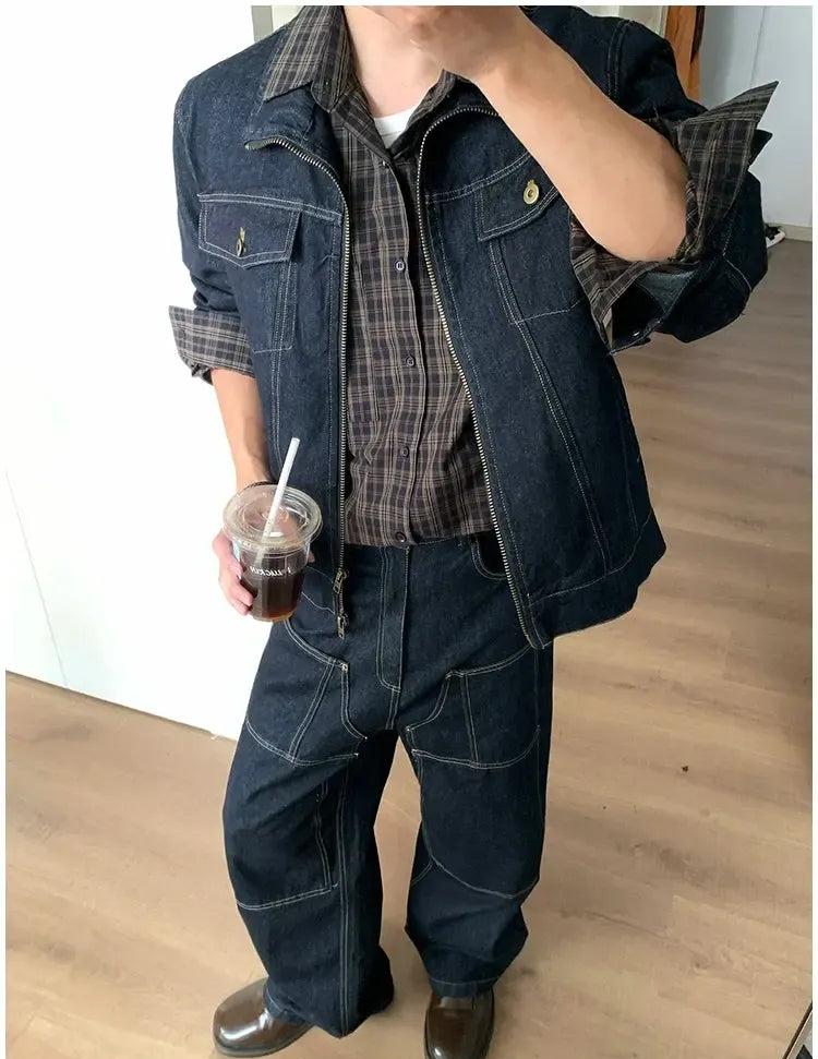 A person wearing a denim jacket, plaid shirt, and jeans is holding a drink in a clear plastic cup with a straw.
